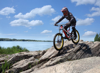 Fototapeta na wymiar Sportsman in sportswear on a mountain bike rides on the stones in the extreme style of downhill