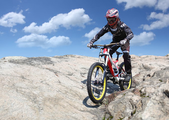 Sportsman in sportswear on a mountain bike rides on the stones in the extreme style of downhill