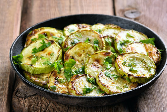 Fried zucchini with herbs in pan