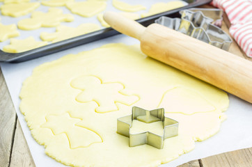 The process of baking cookies at home, closeup on cookie cutter on dough and rolling pin on a wooden board