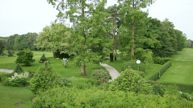 Camera view from left to right. Trees, plants and a little cabana at a golf course in germany.