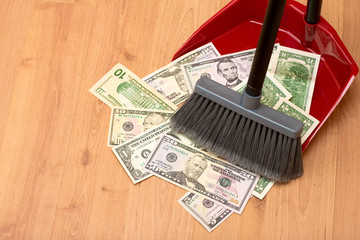 Broom sweeps dollars in the garbage scoop