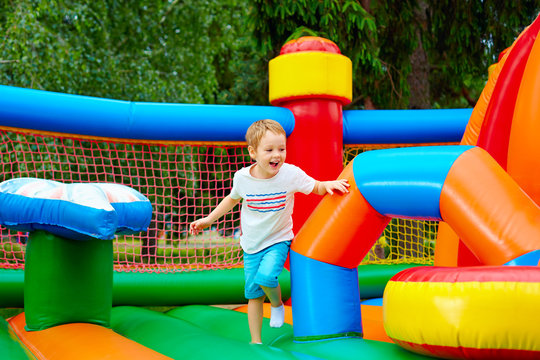 happy excited boy having fun on inflatable attraction playground