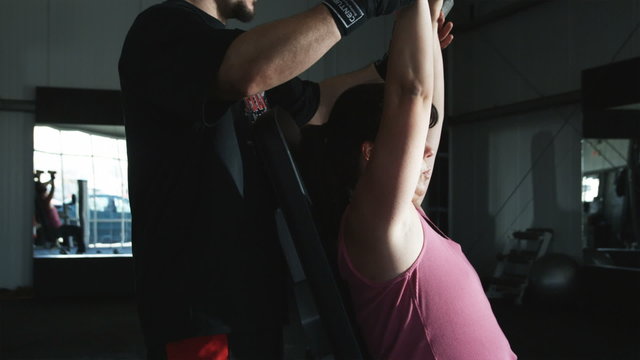trainer helping a female client do military press with dumbbells