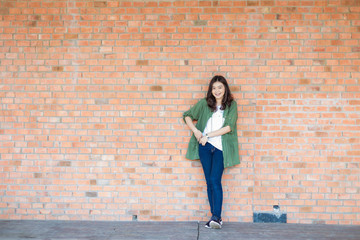 Happy asian woman with black Hair standing Against Old Brick Wal