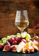 White wine, cheese, figs, nuts and grapes on the old wooden back