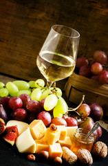 White wine, cheese, figs, nuts and grapes on the old wooden back
