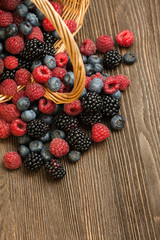 different berries in a basket on a wooden table