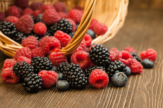 different berries in a basket on a wooden table