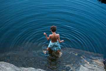 boy standing in a lake surrounded by ripples, shot from above