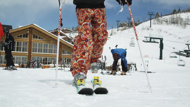 skier clicking into her skis and skiing away