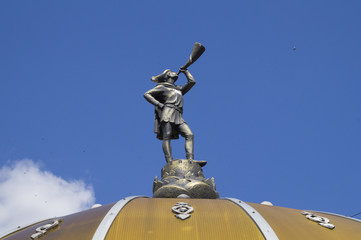 Статуя мальчика с трубой на крыше здания