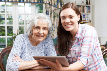 Teenage Granddaughter Showing Grandmother How To Use Digital Tab