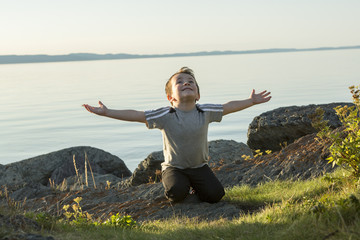 Boy pray at the sunset closer to the beach