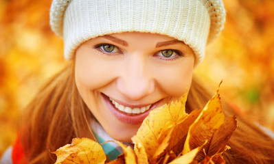 face of happy girl with autumn leaves on walk