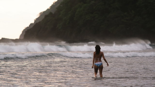 woman in a bikini walking into the surf