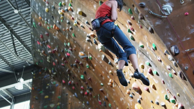 woman being lowered from an indoor climbing wall
