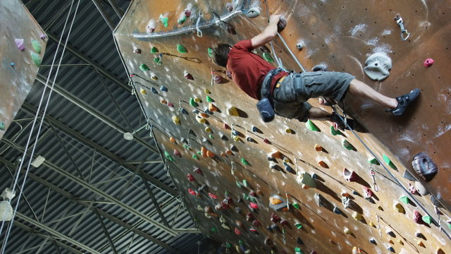 man climbing on an indoor climbing wall
