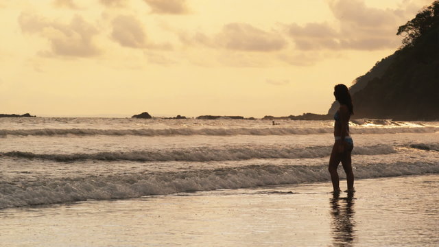 woman in a bikini standing in the surf