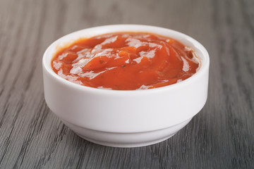 white bowl with tomato sauce on wood table