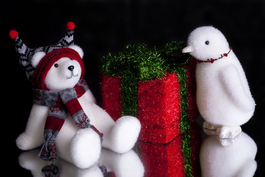 Christmas present with fluffy polar bear with a scarf on  and a penguin shot front on on a black background