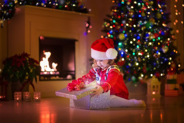 Kids opening Christmas presents at fireplace