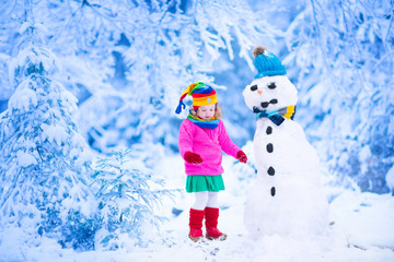 Fototapeta na wymiar Little girl building a snow man in winter