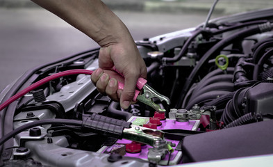 Jumper cables charging battery on a car.