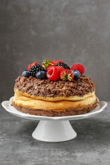 Cheesecake with chocolate topping decorated with summer fruits