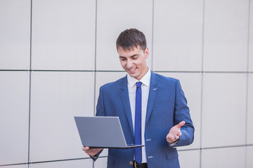 Successful businessman standing in the street holding a laptop