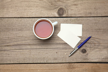 Blank business cards with pen and tea cup on wooden office table