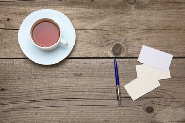 Blank business cards with pen and tea cup on wooden office table