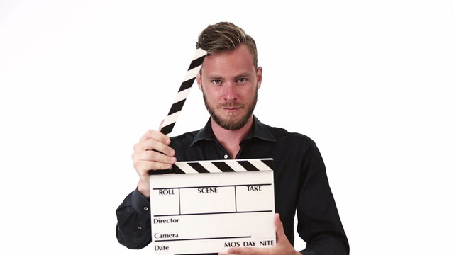 Attractive movie worker wearing a black shirt, holding a movie slate, clapping in front of camera. White background.