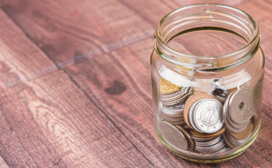 Japanese Yen coins in a mason jar over wooden background