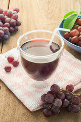Grapes juice in glass with a cloth on a wooden floor.