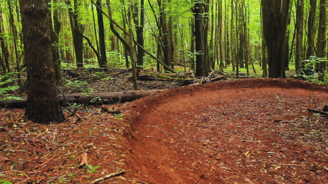 Intense Mountain Biking Follow Cam Shot Around Steep Dirt Berm Going Fast. Outdoor Active Lifestyle in the Forest.