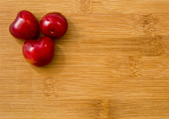 Dojrzałe czerwone owoce czereśni na desce.   Tło z kilkoma owocami czereśni na bambusowej kuchennej desce. © IreneuszB