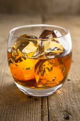 Vertical shot of lone glass of whisky bourbon on the rocks ice vintage reclaimed wood 