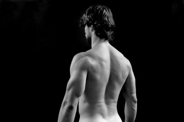 Fototapeta na wymiar back view of a shirtless man on black background