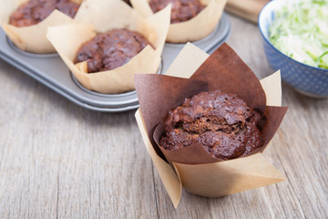 Flourless chocolate courgette muffins in a muffin tin, on a wooden table