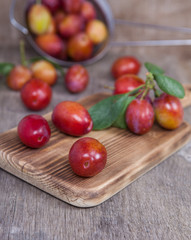 Freshly picked plums with the leaves on a wooden board, on the dark table, selective focus