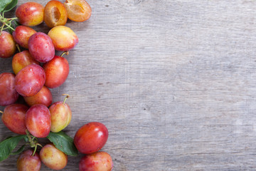 Freshly picked plums with the leaves on the dark table with the space for the text, above view, selective focus