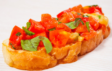 Italian tomato bruschetta with chopped vegetables, herbs, cheese and oil on grilled or toasted...