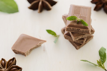 Stack of chocolate bar pieces with mint on  white