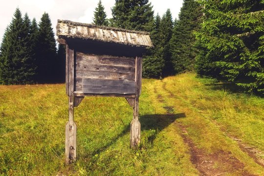 Mountain road sign,made out of wood next to hiking trail.