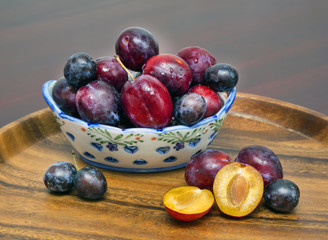 vase with plums. wooden tray