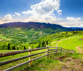 fence on hillside meadow in mountain at sunrise