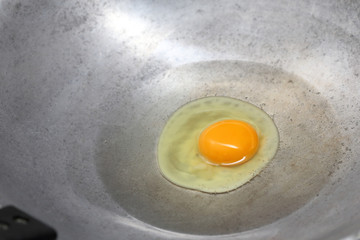 cooking fried egg in hot pan with oil