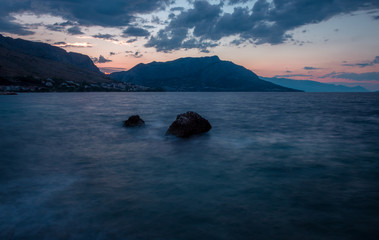 Sunrise Coastline Over Cliffs with Early Morning Clouds and Small Rock Formations in Foreground
