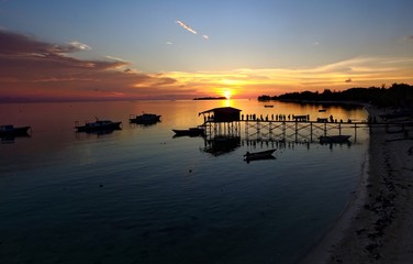 sunset and silhouette people at jetty from aerial view